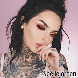 Tattooed woman with dark hair and orange eye makeup  @bellejorden